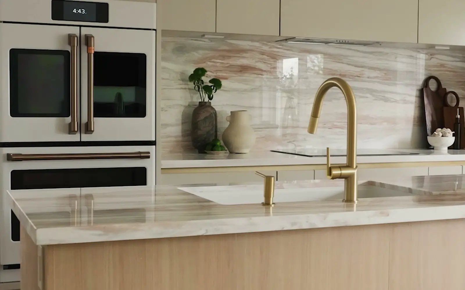 A kitchen with white wall ovens, a pink-veined marble backsplash and a brass tap on an oak island, in a Jarvis Contracting renovation in Toronto